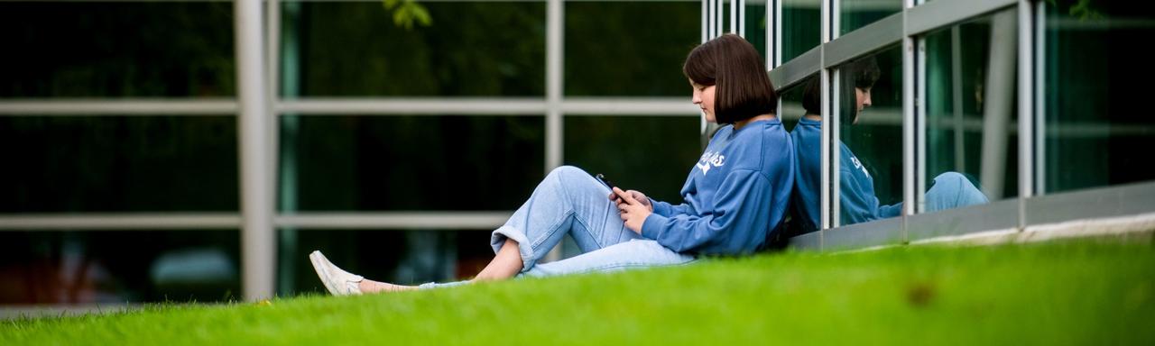Student sitting in the Calder Arts Center Front Lawn
